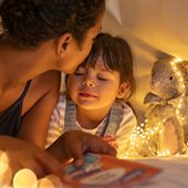 Mother and daughter in a play tent with toys and fairy lights