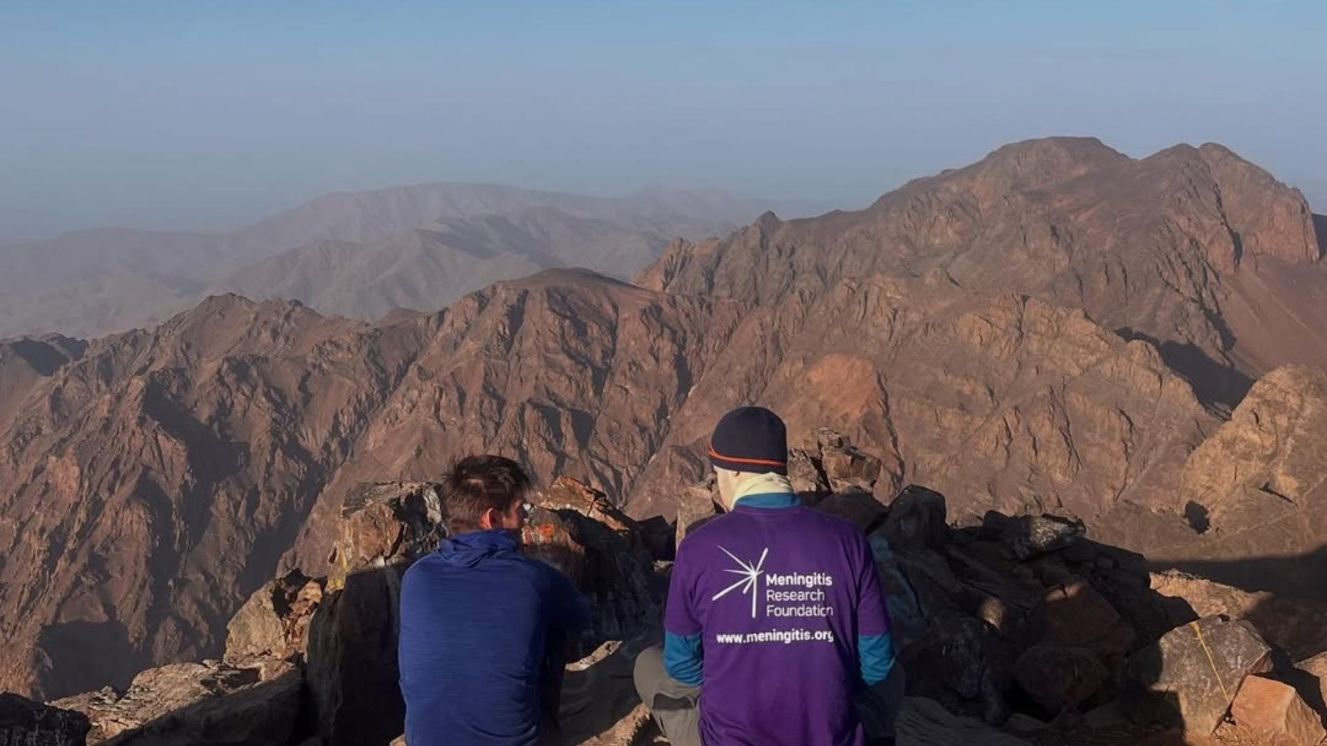 Two students in Meningitis Research Foundation Tshirts on a mountain.