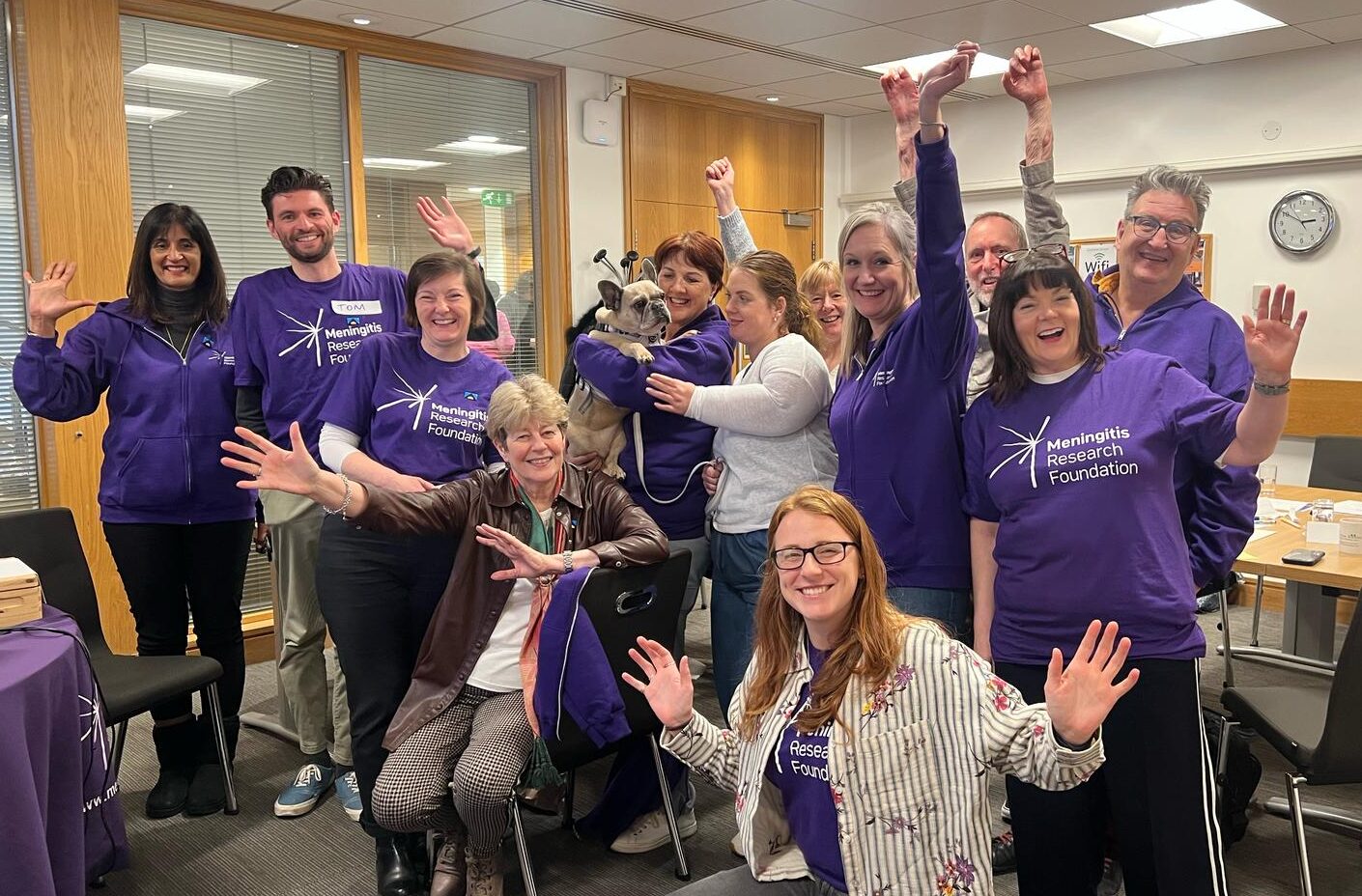 A group of people cheering and waving at a meeting in Birmingham.
