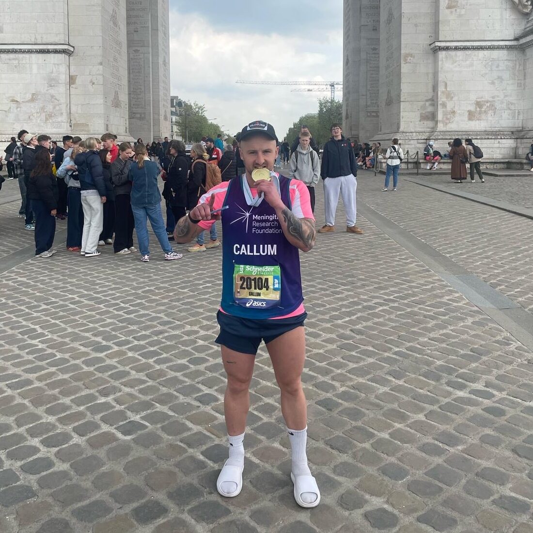 Callum Strang holding medal and wearing his MRF running vest, in Paris.