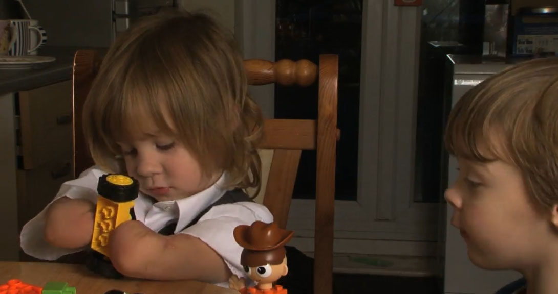 A video still of Charlotte playing with a child's toy