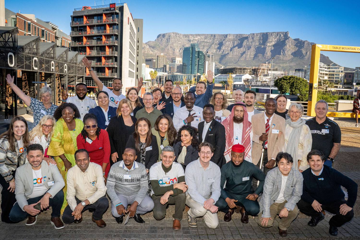 Photo of CoMO members in 3 rows in front of Table Mountain in Cape Town.