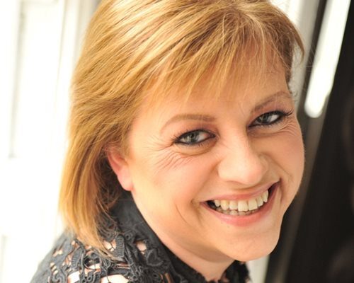 A woman with short blonde hair smiling.