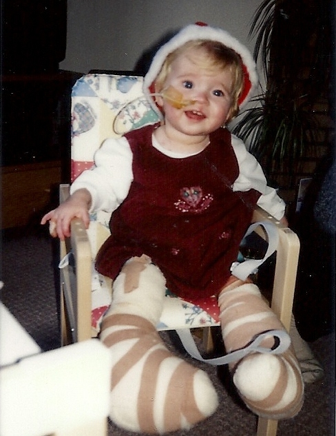Ella Bailey in a christmas outfit as a baby, covered in bandages