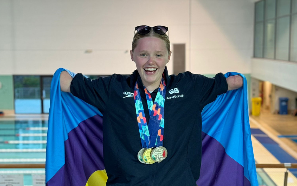 Ellie Challis with her paralympic medals holding the meningitis flag