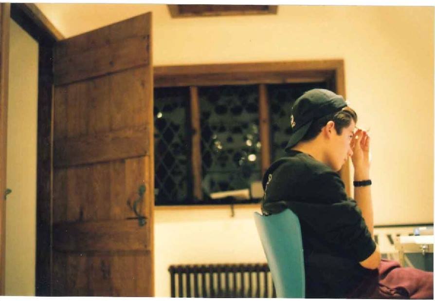 A photograph of a boy sitting on a chair facing away from the camera