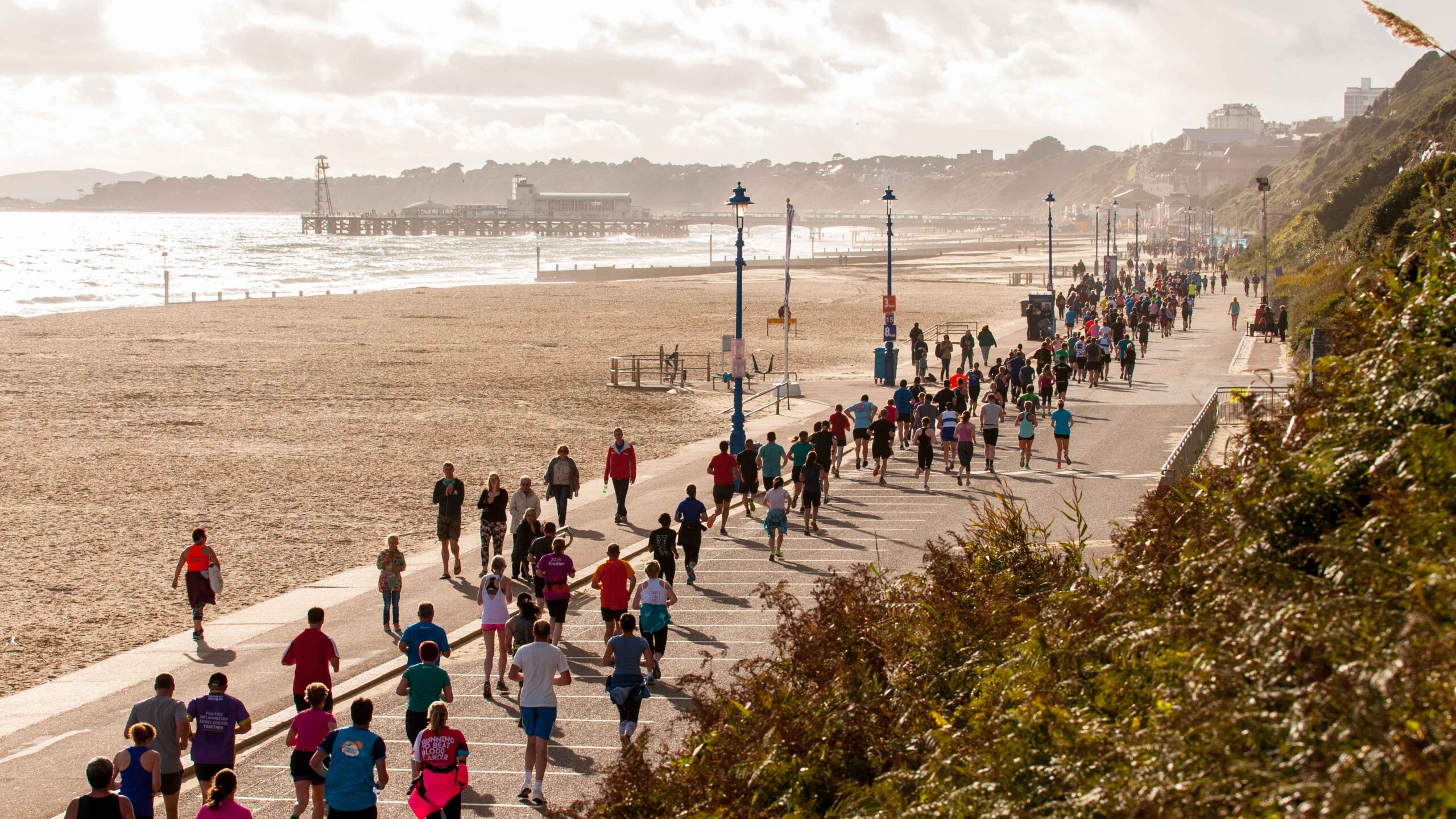 Group of people running alongside the beach in Bournemouth.