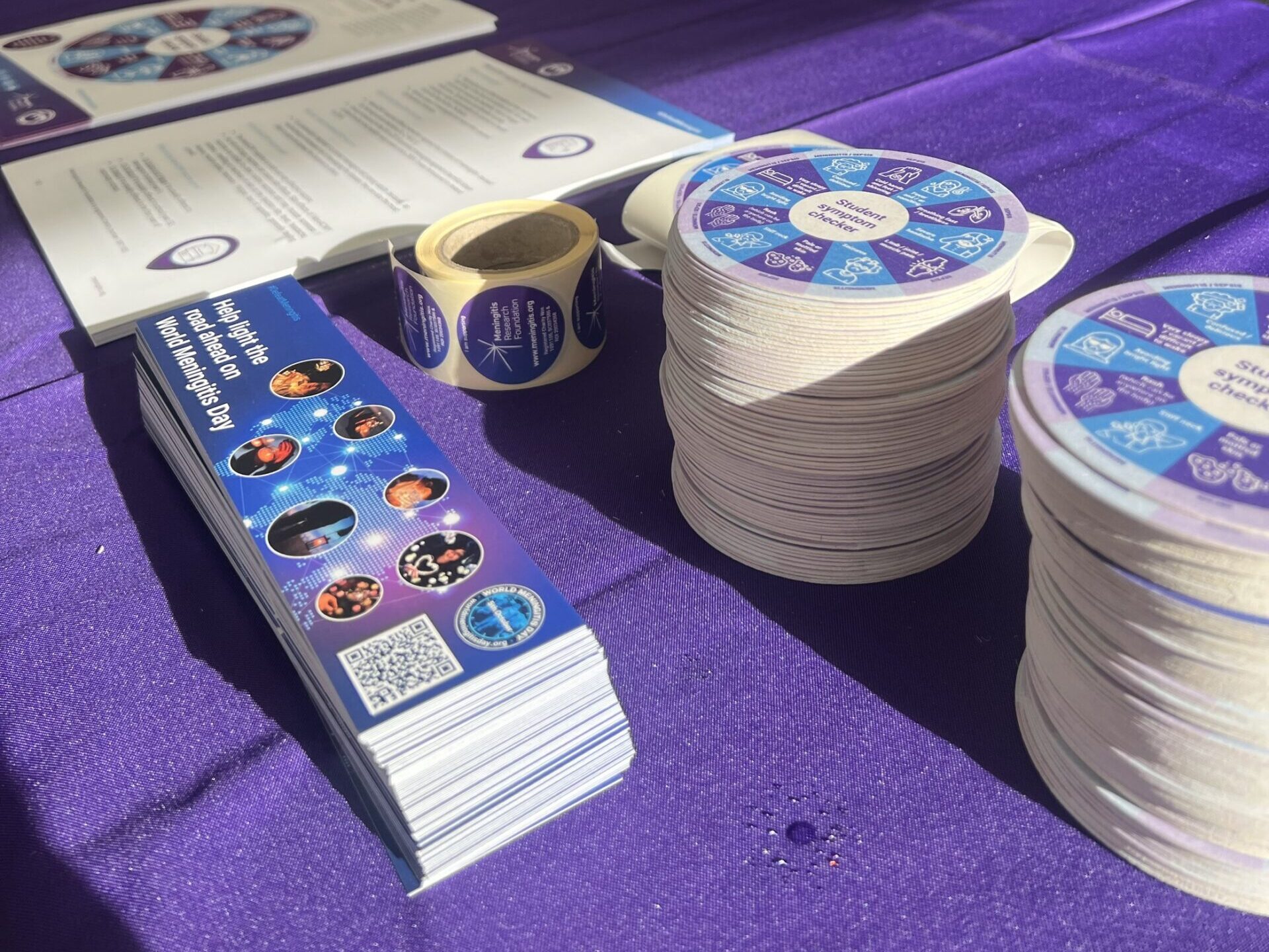 Meningitis Research Foundation materials laid out on a purple tablecloth.