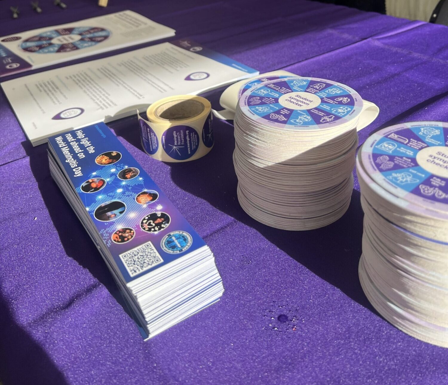 Meningitis Research Foundation materials laid out on a purple tablecloth.
