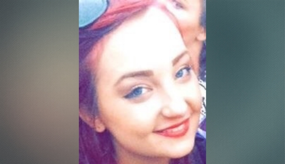 A young woman with red hair and blue eyes smiling.