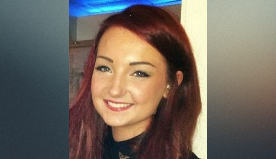 A young woman with red hair and blue eyes smiling.