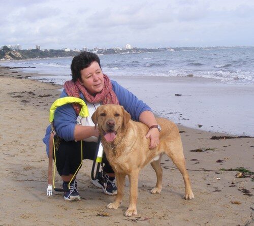 A photograph of Julie Coakley on the beach with a guide dog