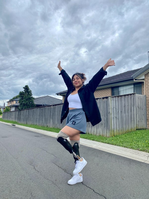 Juttima Chinnasri wearing prosthetic legs and smiling with her arms in the air