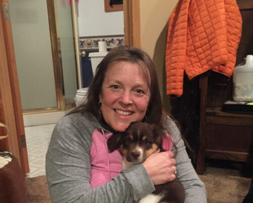 A photograph of Laurie Perry holding a puppy