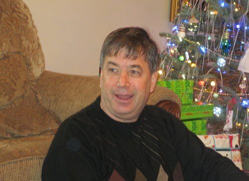 A photograph of Lee Holztrager with a christmas tree.