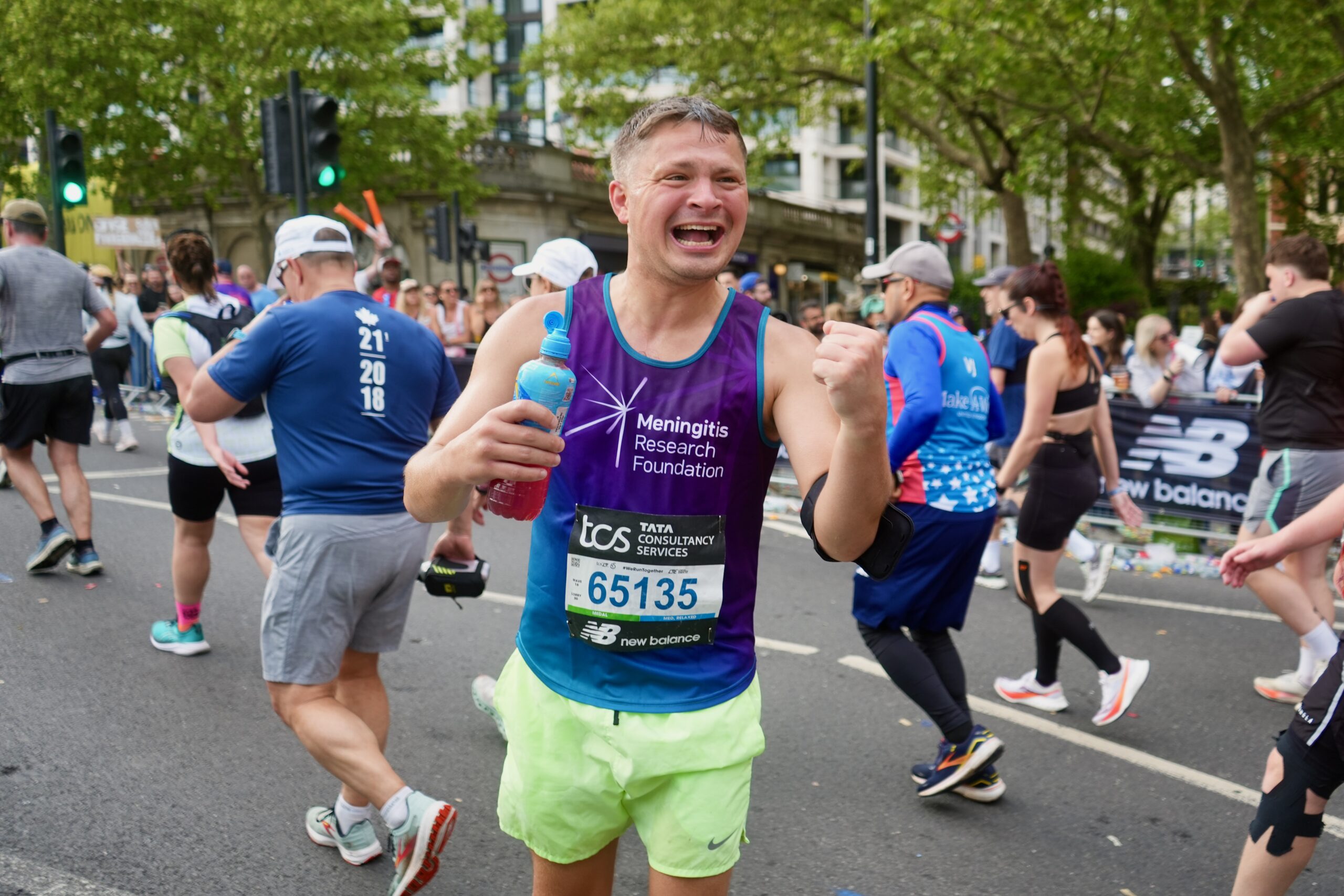 A London Marathon runner punches the air with joy.