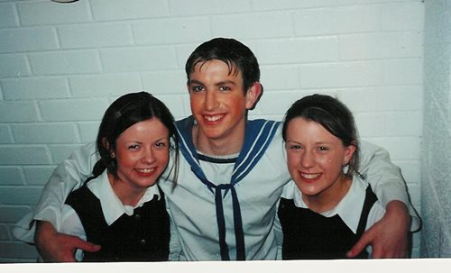 A photograph of Philip Brady dressed as a sailor with his arms around two girls