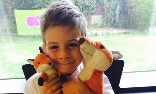 A photograph of Reilly holding two stuffed fox toys