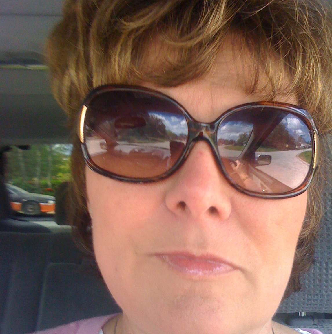 A photograph of Robin Owens in a car wearing sunglasses