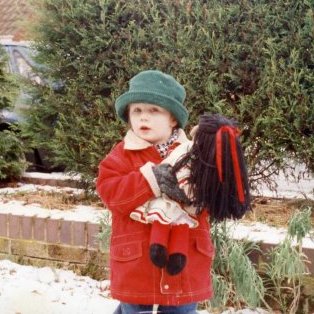 A photograph of Sophie outside in the snow holding a doll