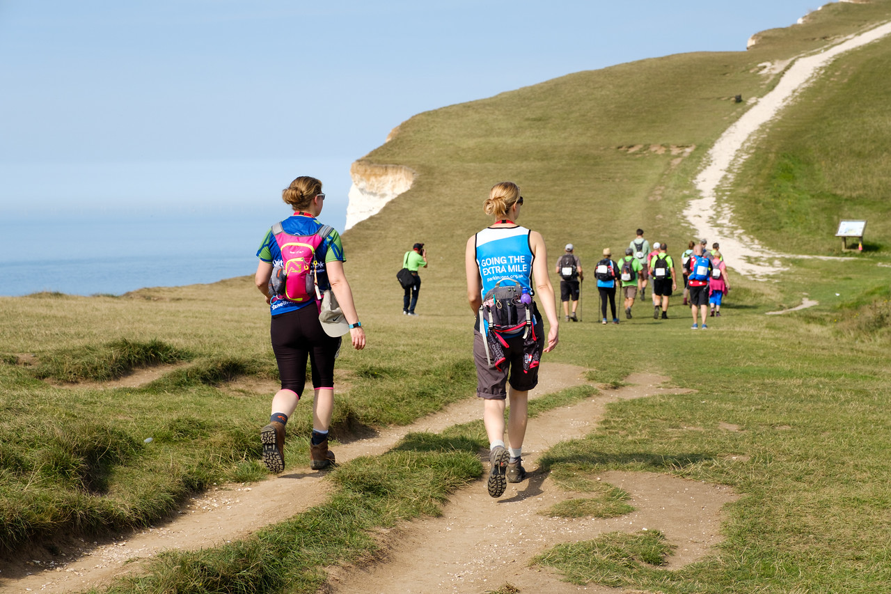 People walking along a path at the top of cliffs, wearing exercise clothing.