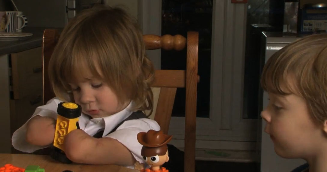 A video still of Charlotte playing with a child's toy