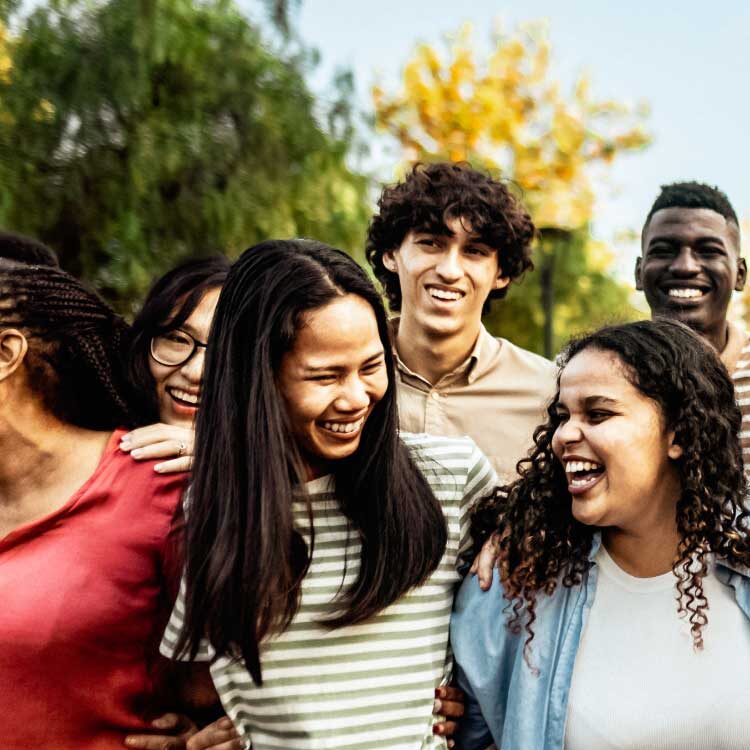 Group of laughing people standing arm in arm.