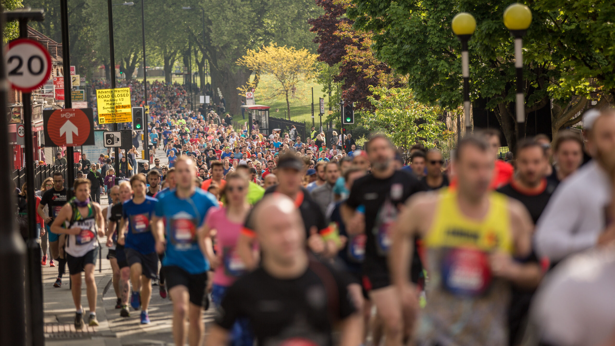 Crowd of people running up a hill alongside a park.