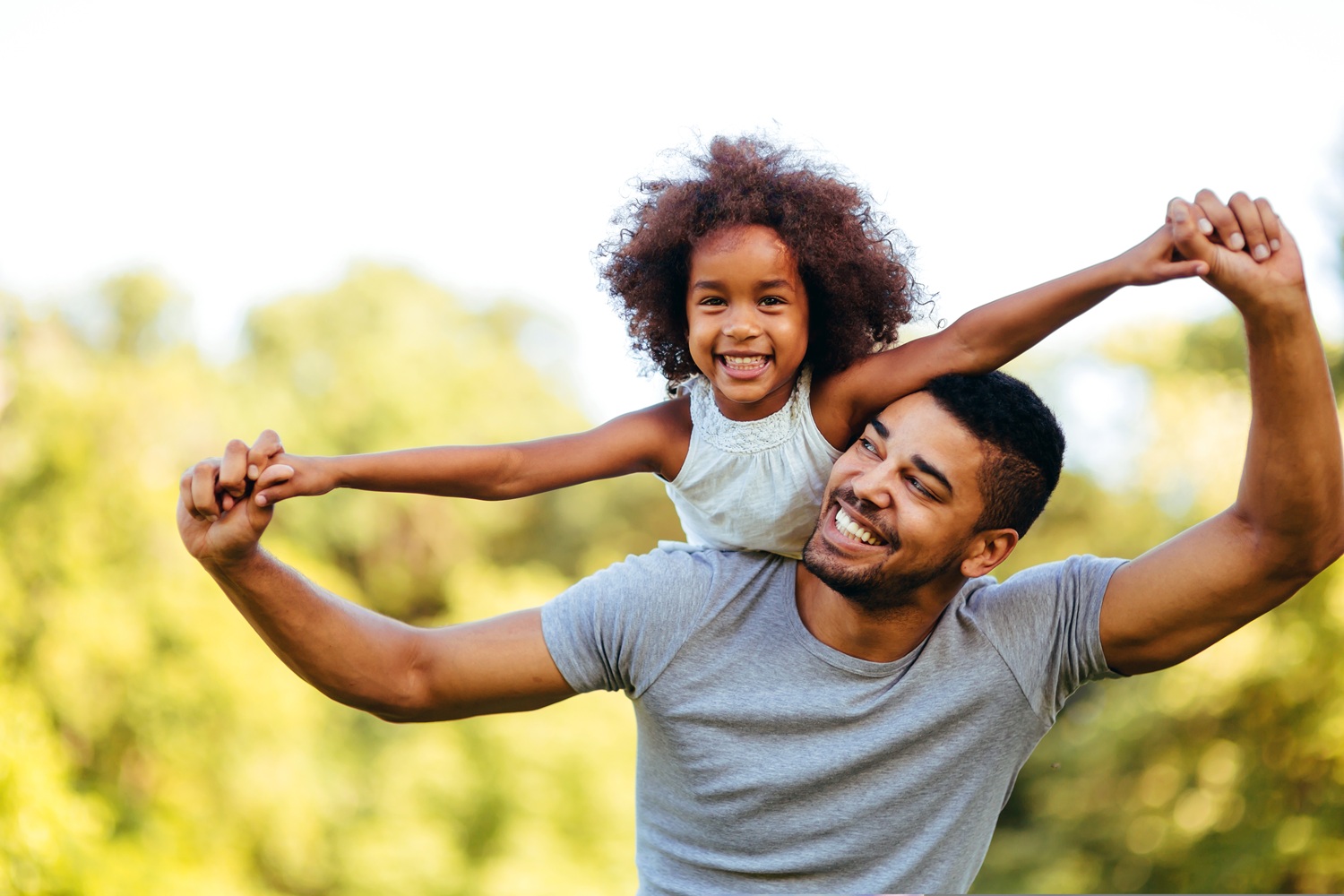 A man with his son on piggyback in a field.