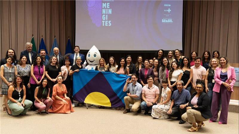 Suelen (centre) with other representatives at the launch of the Brazilian national plan​ holding up the Meningitis Flag