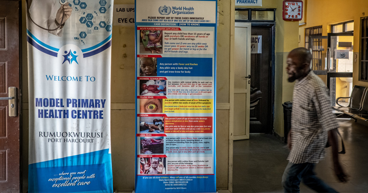 Photo of a man walking past a poster in a medical centre