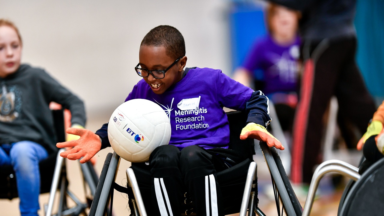 Boy in wheelchair playing a ballgame with others.