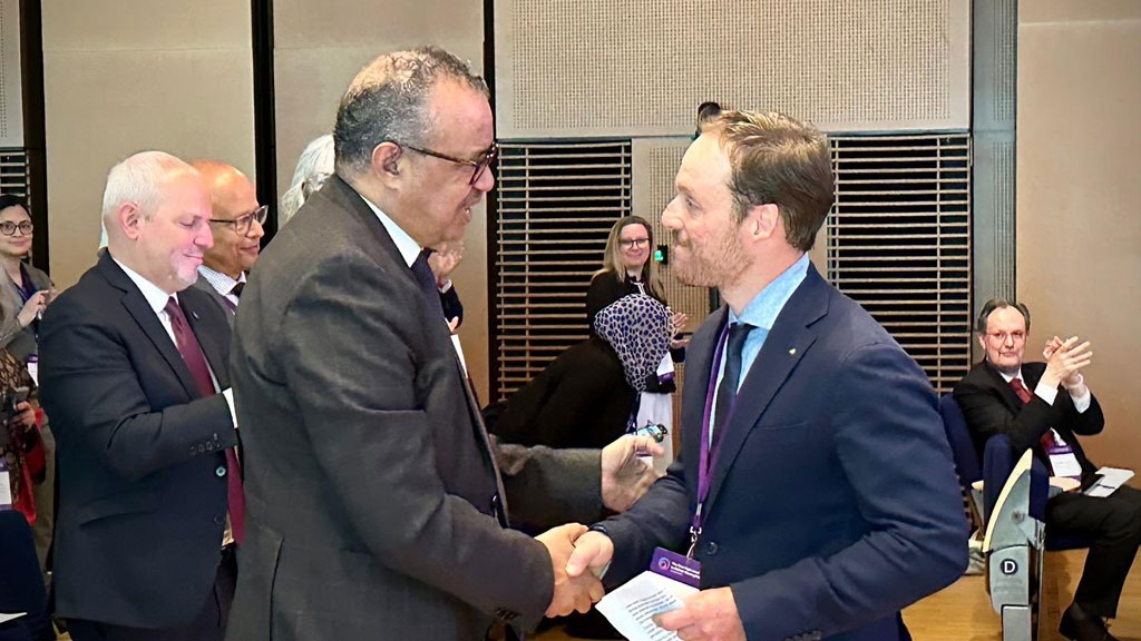 Two men shaking hands at the WHO's high-level meeting.