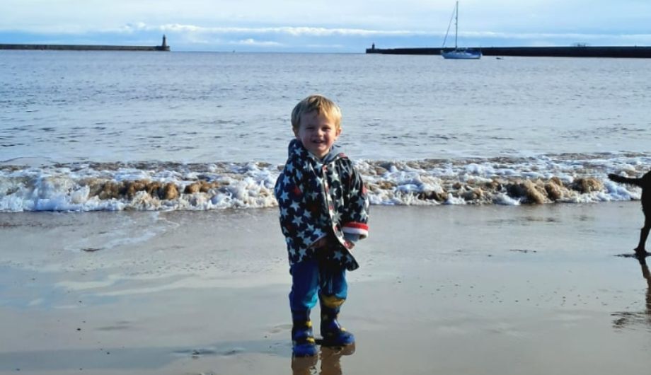 A young boy smiling on the beach