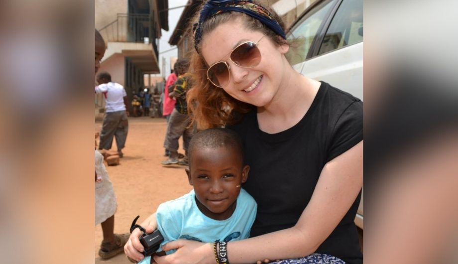 A women in a black t-shirt and sunglasses hugging a schoolchild.