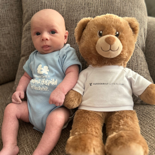 Wyatt sat on a chair next to a teddy bear.