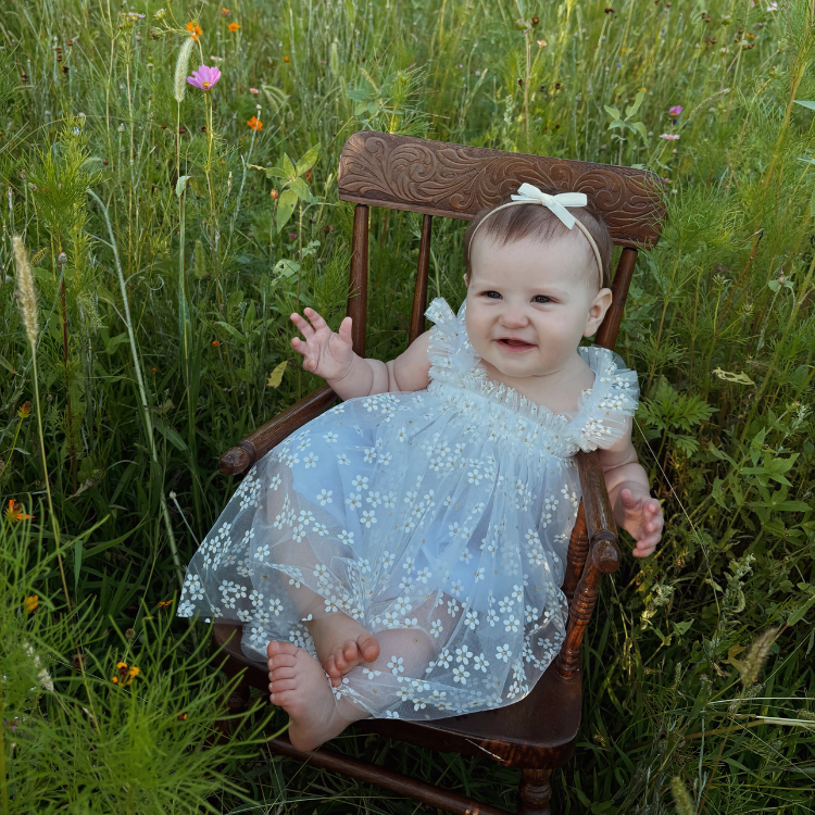 A young baby sat on a chair in a field