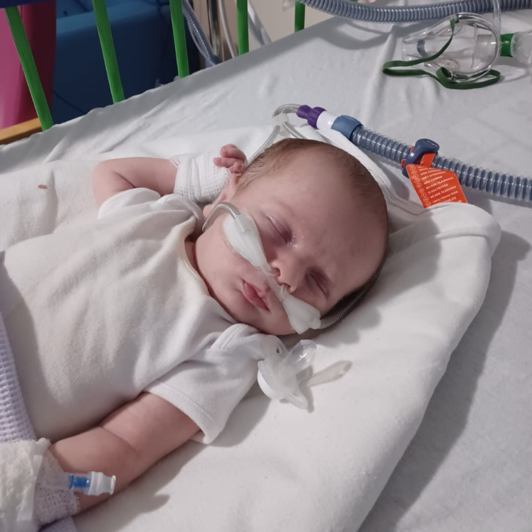A young baby in hospital with a tube up his nose
