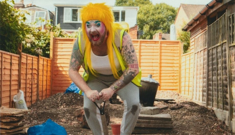 Ginny Lemon dressed in their drag outfit in a garden