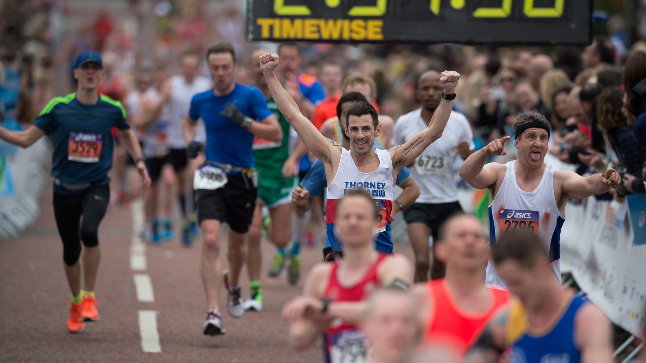 Runner raises his arms in celebration crossing the marathon finish line.